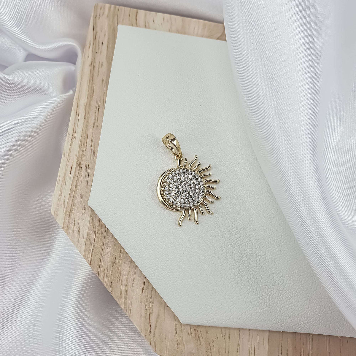 Sun pendant with white cubic zirconia on a wooden board