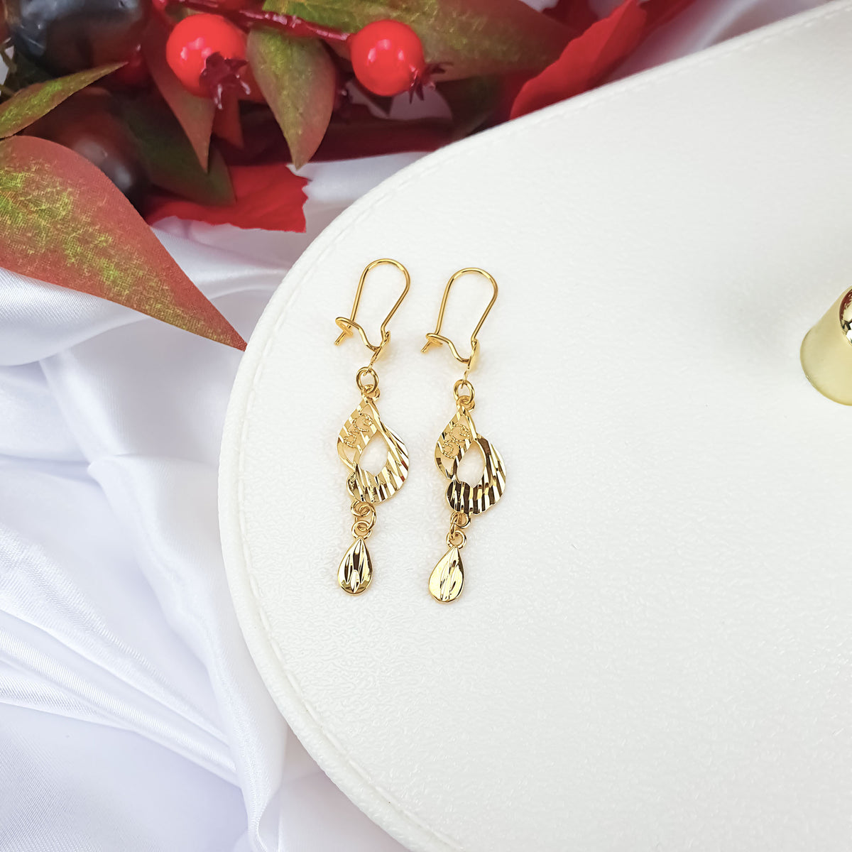 Gold-plated openwork teardrop earrings on a white stand