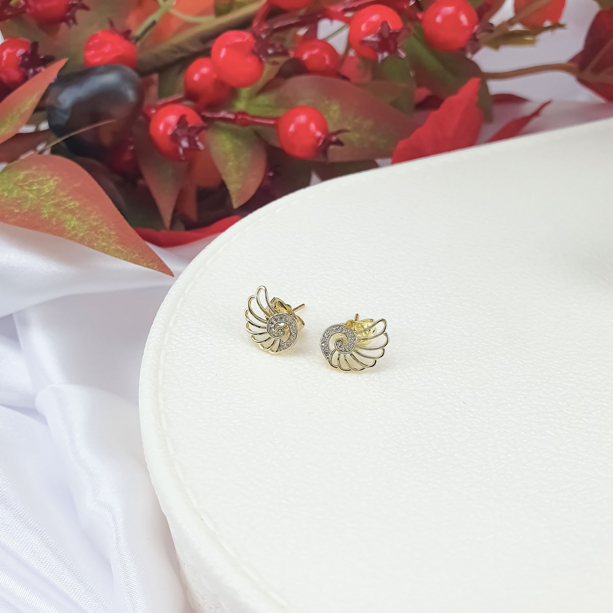 Gold-plated wing studs with a stone spiral and backs on a white stand