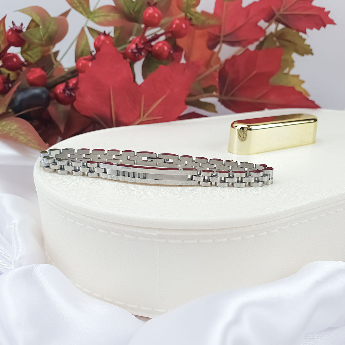 Silver-tone link bracelet on a white jewellery box with autumn leaves