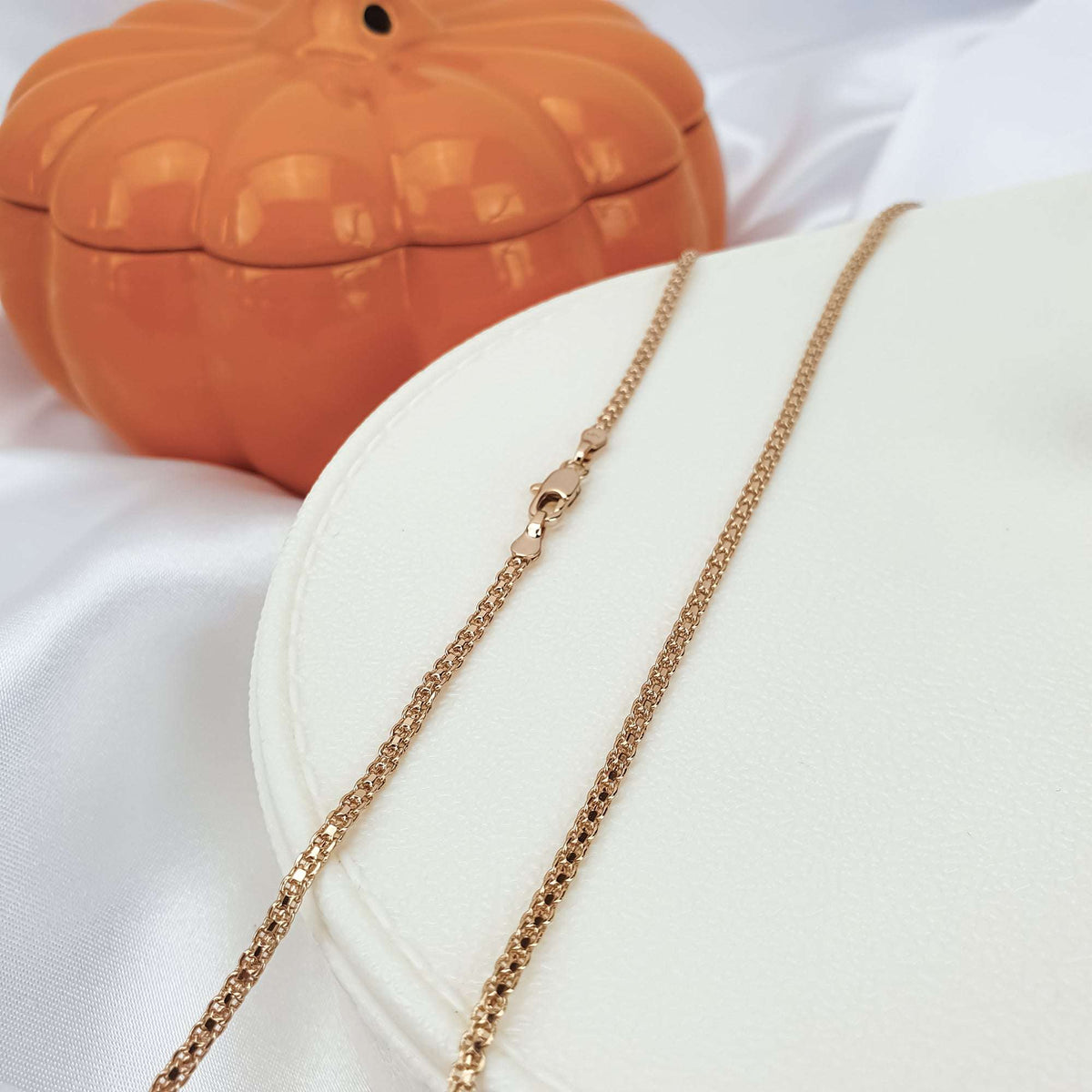 Gold-plated Bismarck chain on a light tray beside an orange pumpkin box