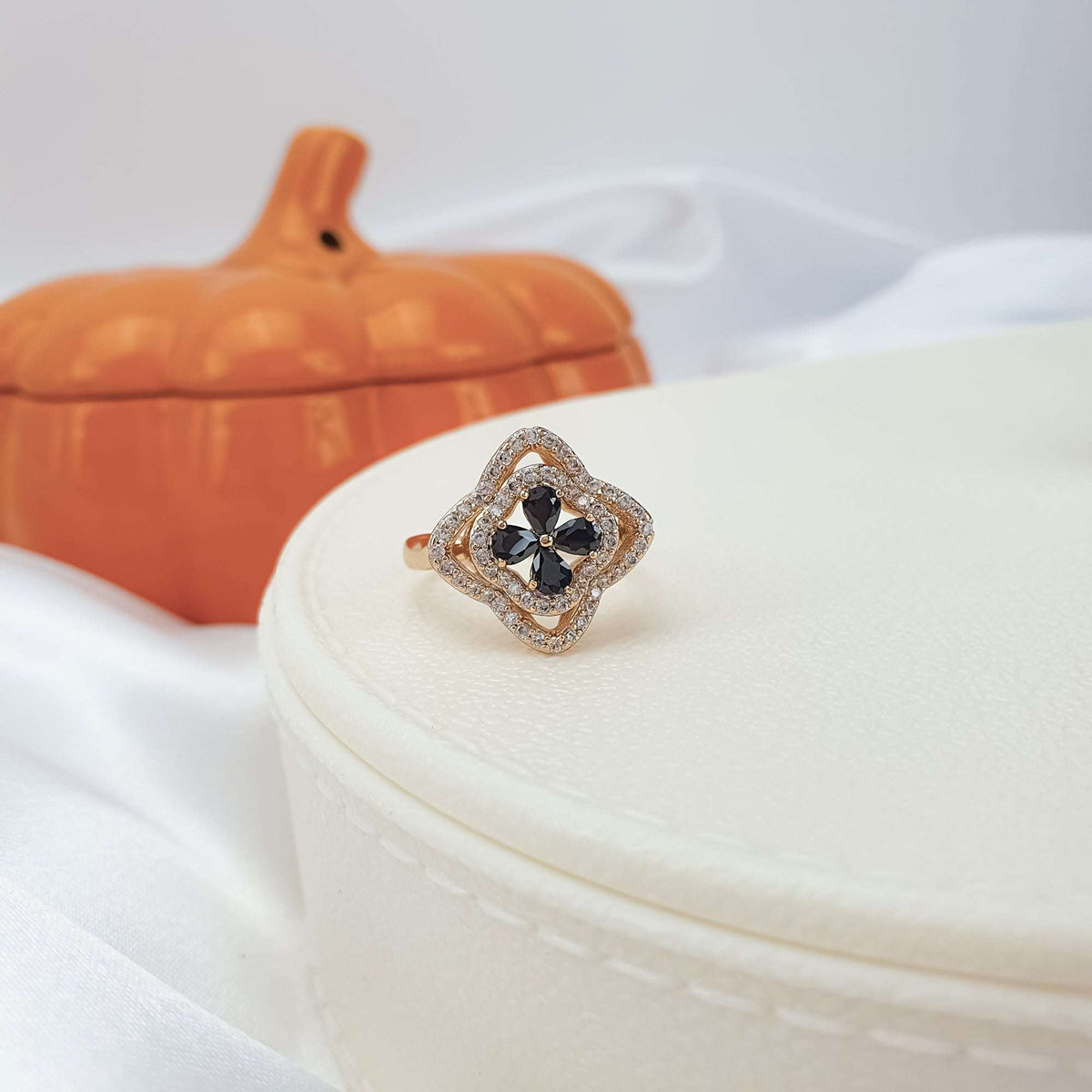 Flower ring with four black stones and white cubic zirconia on a jewellery box