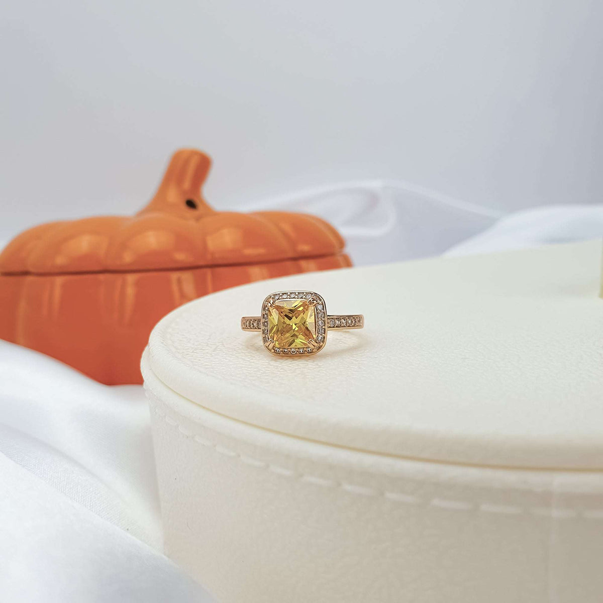 Yellow cubic zirconia ring on a jewellery box, orange pumpkin in the background