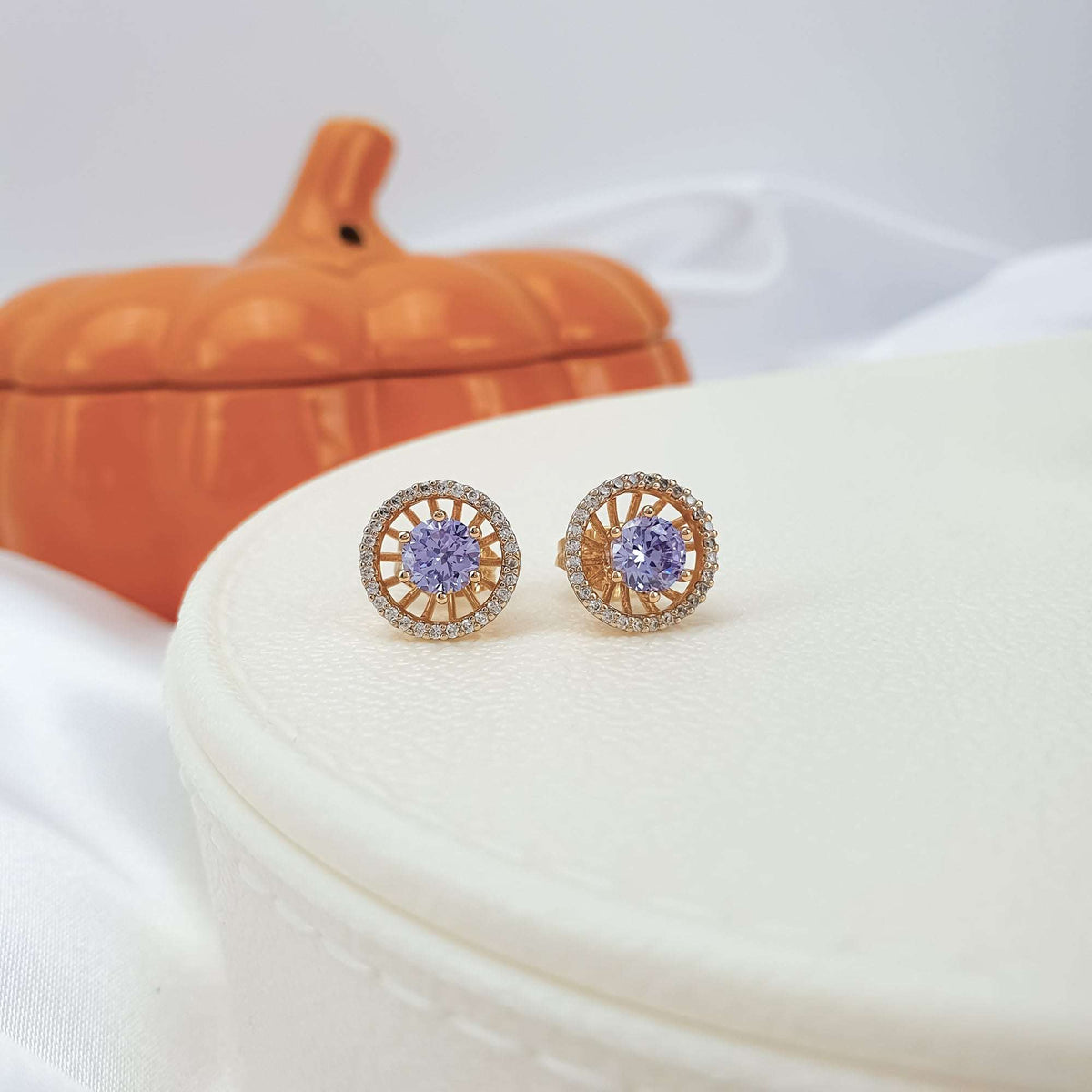 Pair of round violet studs on a white leather box
