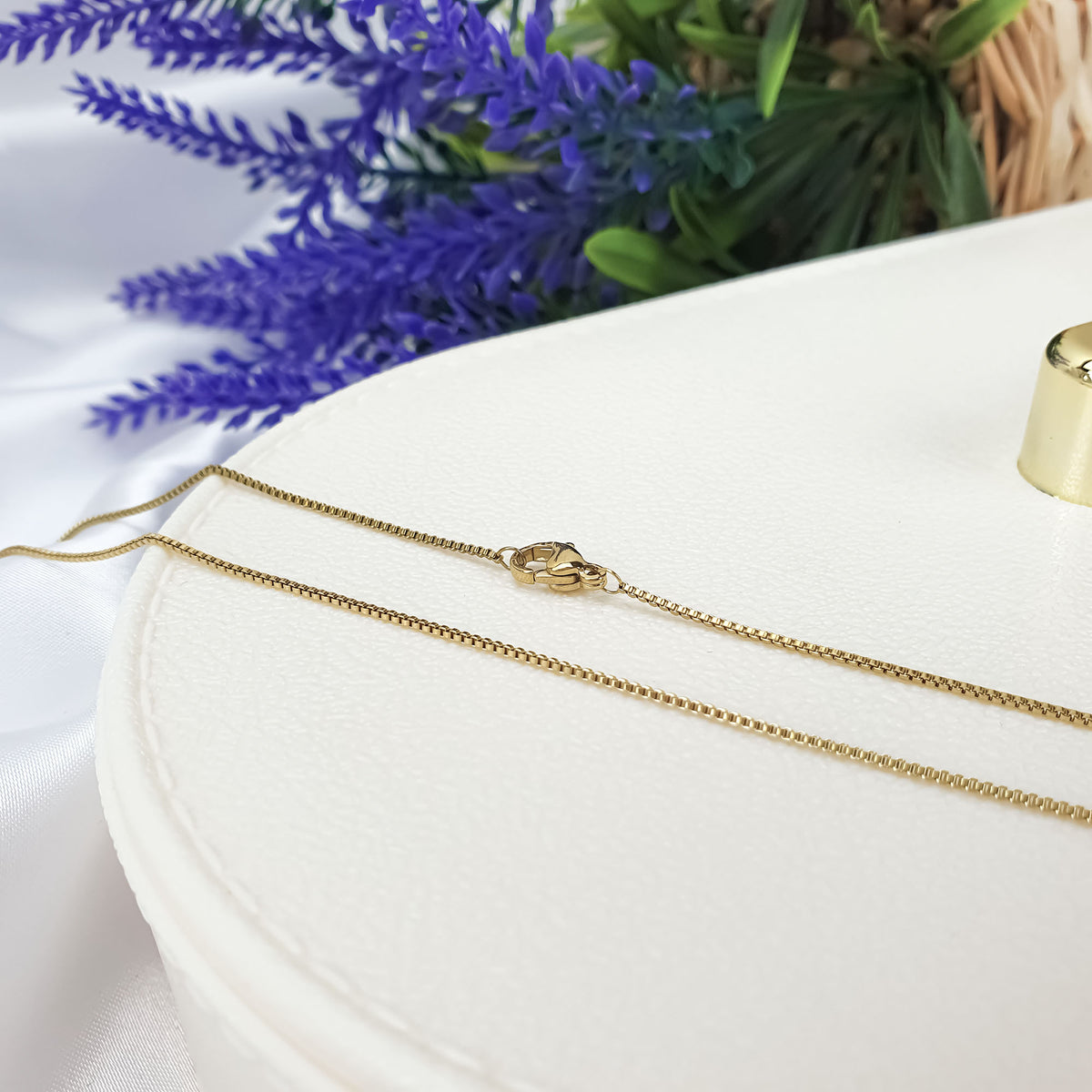 Delicate gold-tone Venetian chain with a lobster clasp on a light surface