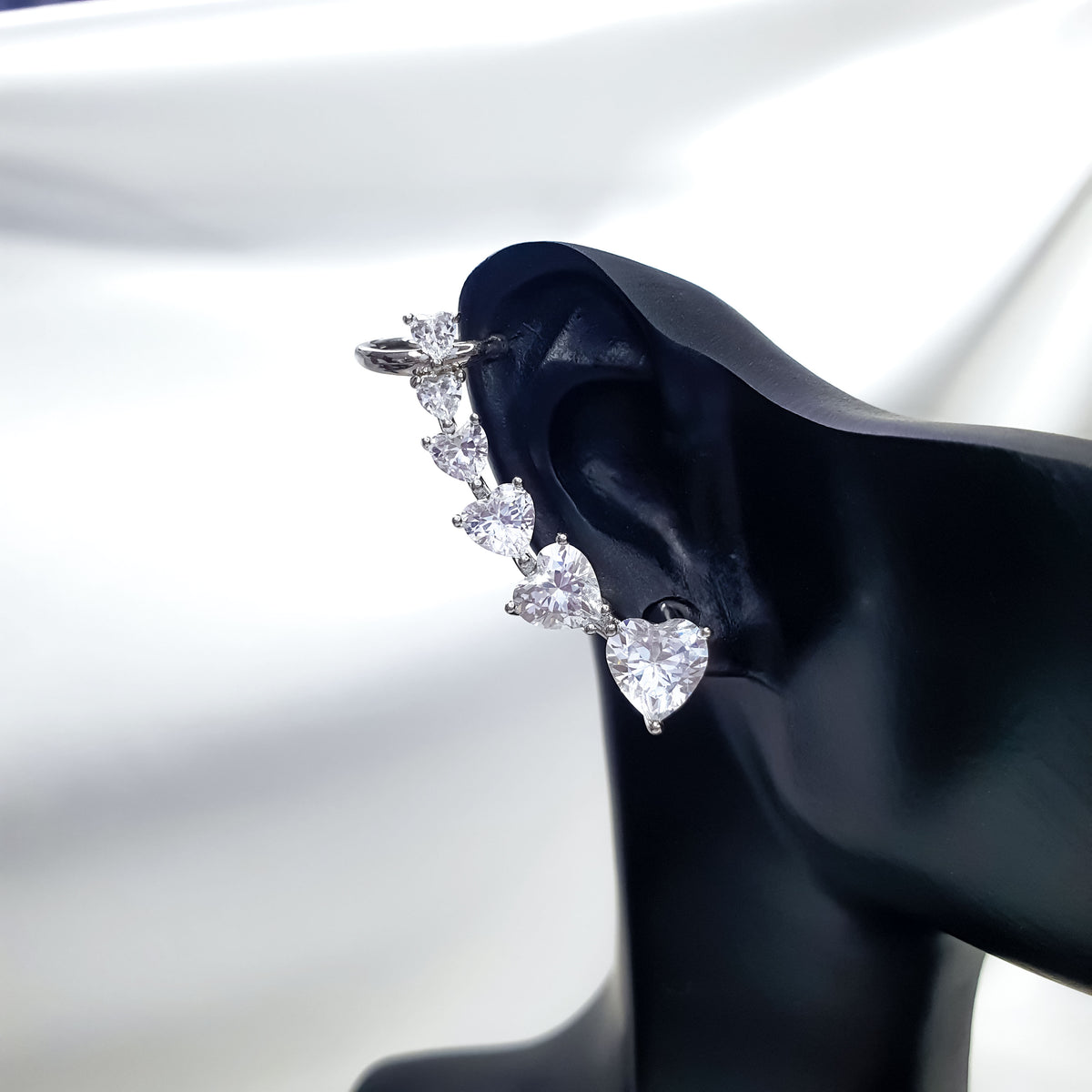 Earring on a black ear display with a rising row of hearts