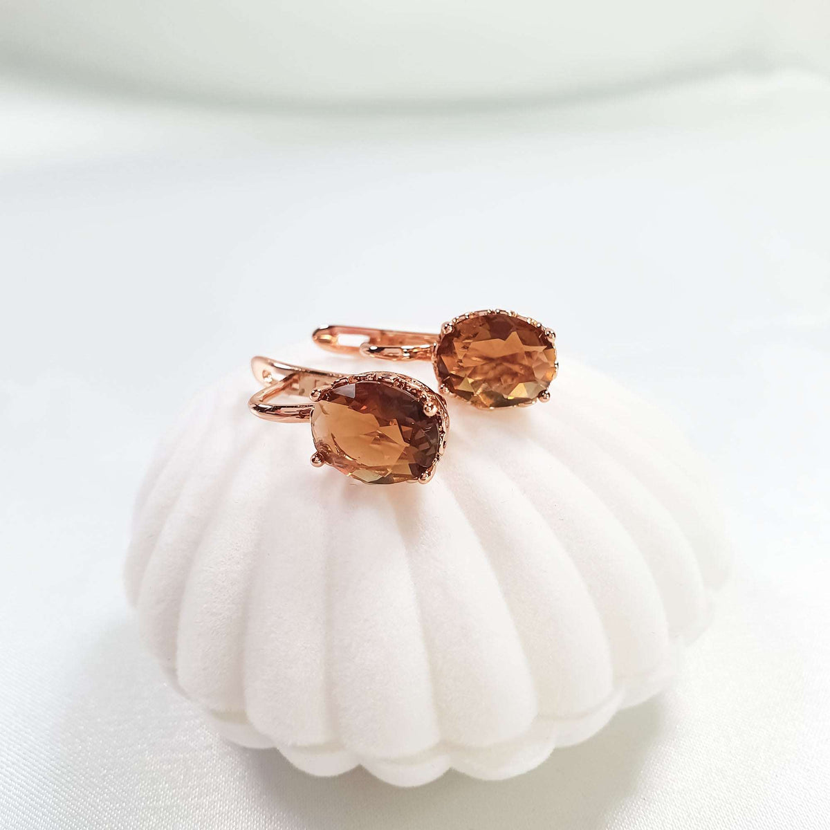Earrings with oval coffee-coloured stones on a velvet stand