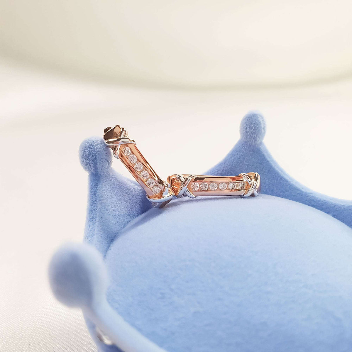 Two-tone earrings close up on a light blue velvet stand