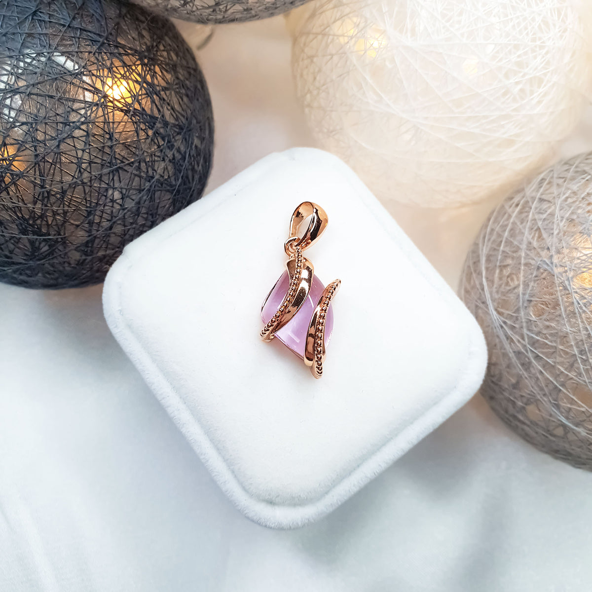 Pink stone pendant with a gold-plated spiral on a white velvet box