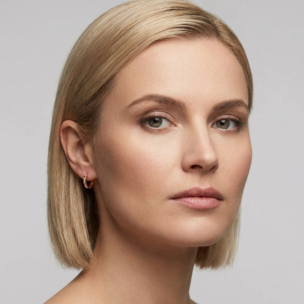 Side close-up of a model wearing a fine gold-tone hoop