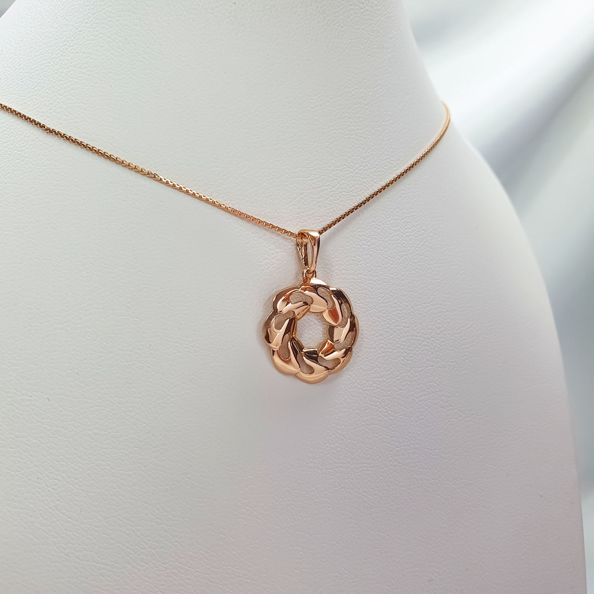 Close-up of the gold-plated pendant and chain on a white neck bust