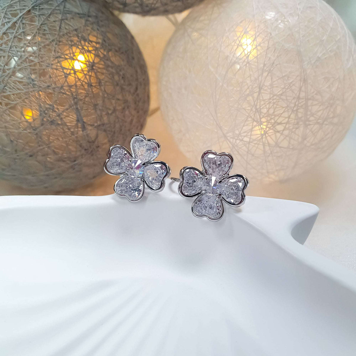 Two clover earrings with heart-cut stones on a white dish