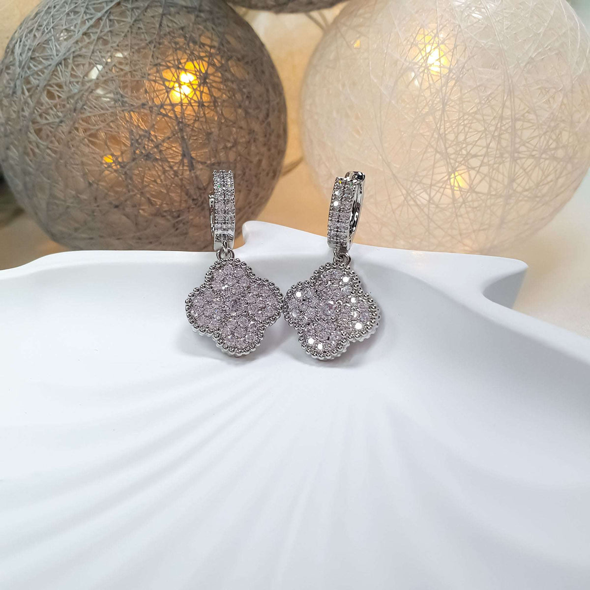 Pair of earrings with pavé clover charms on a white dish