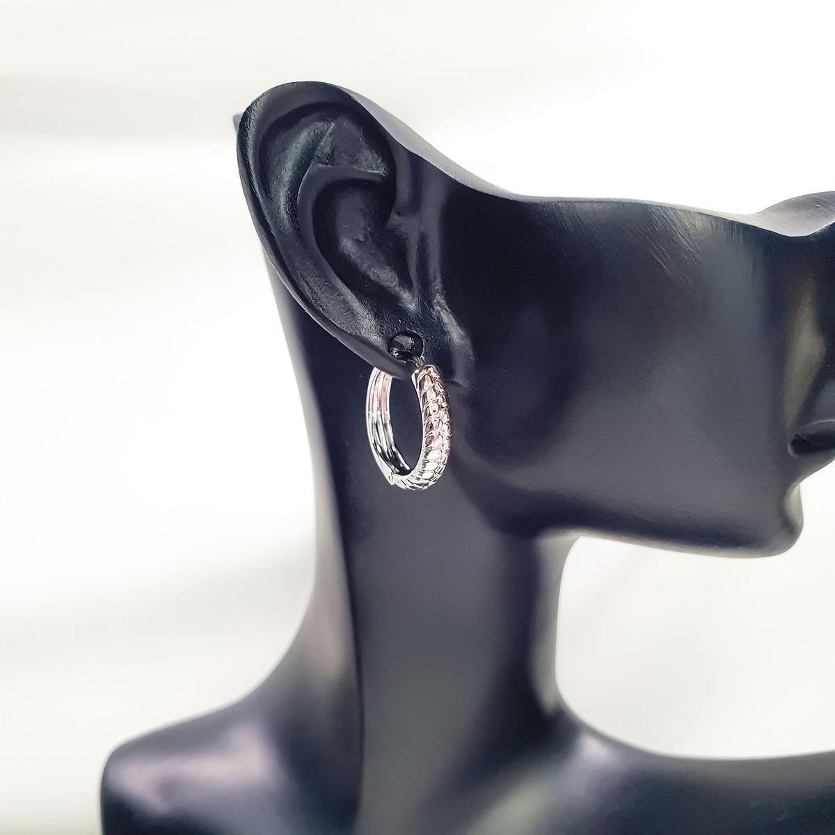 Textured silver-tone hoop with click closure on a black ear display