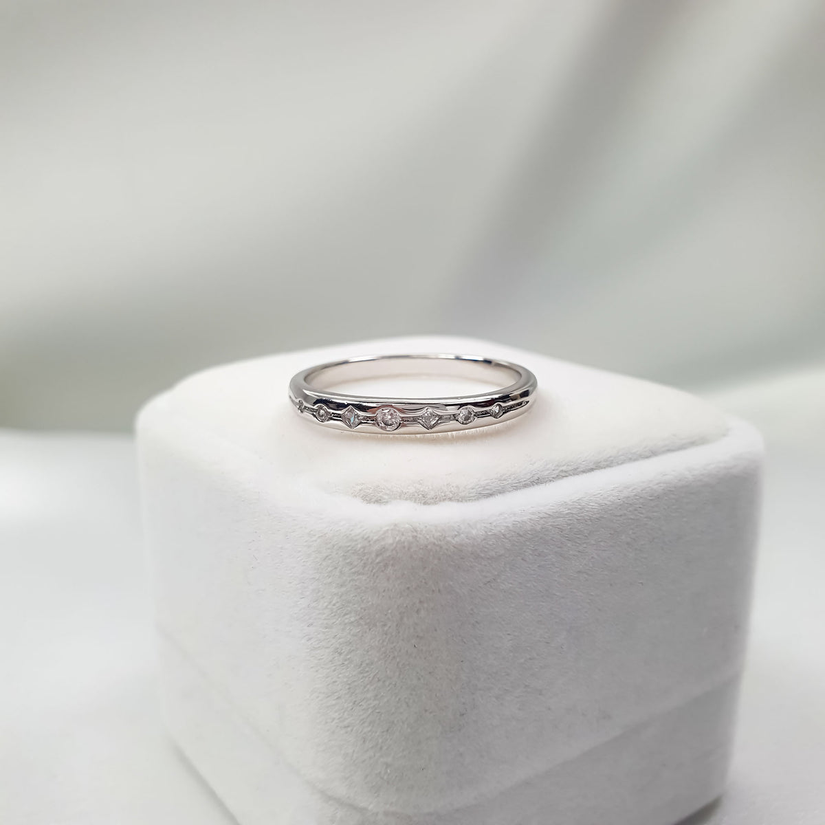 Thin cubic zirconia ring seen from the side on a white velvet box