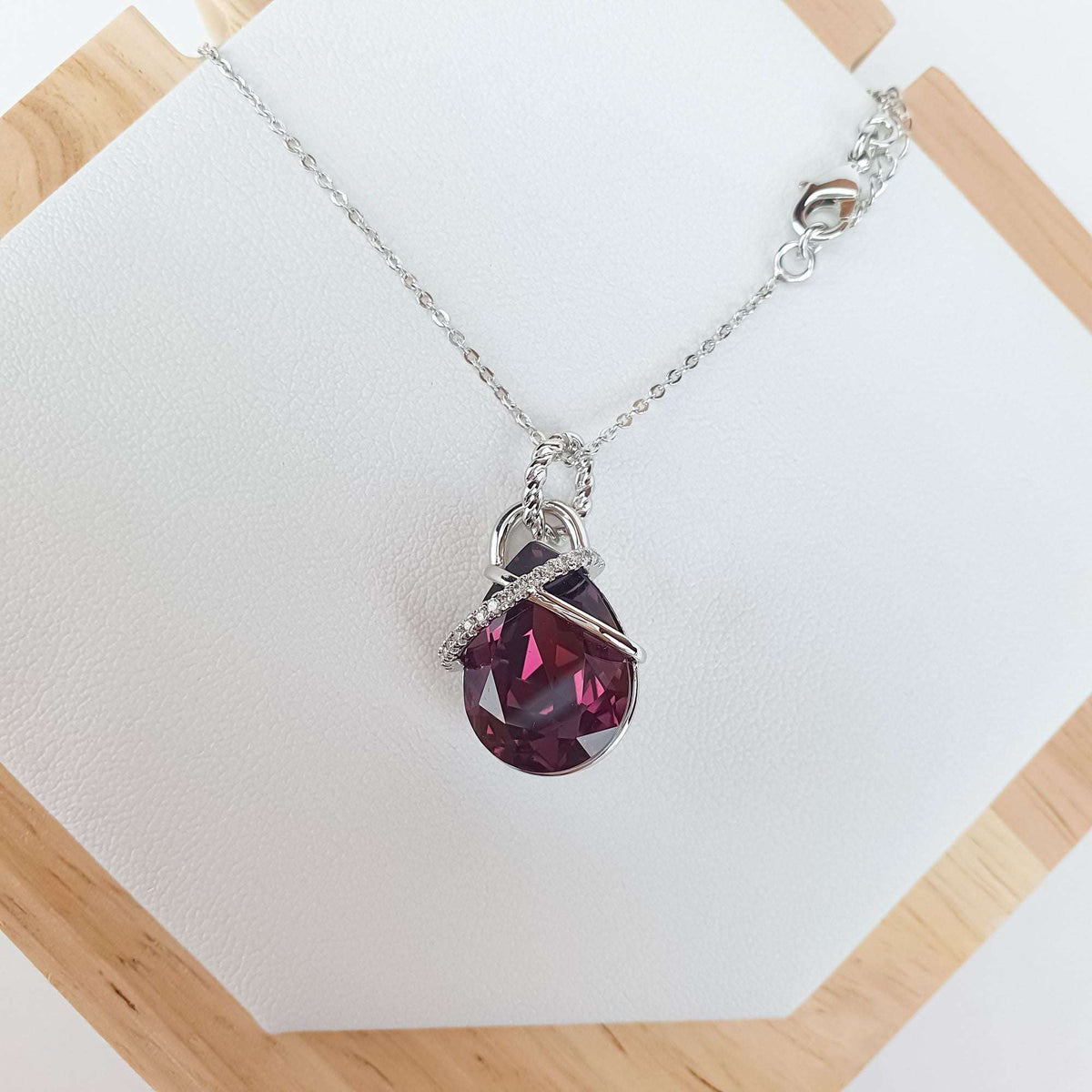 Violet crystal necklace with a cubic zirconia band on a wooden stand