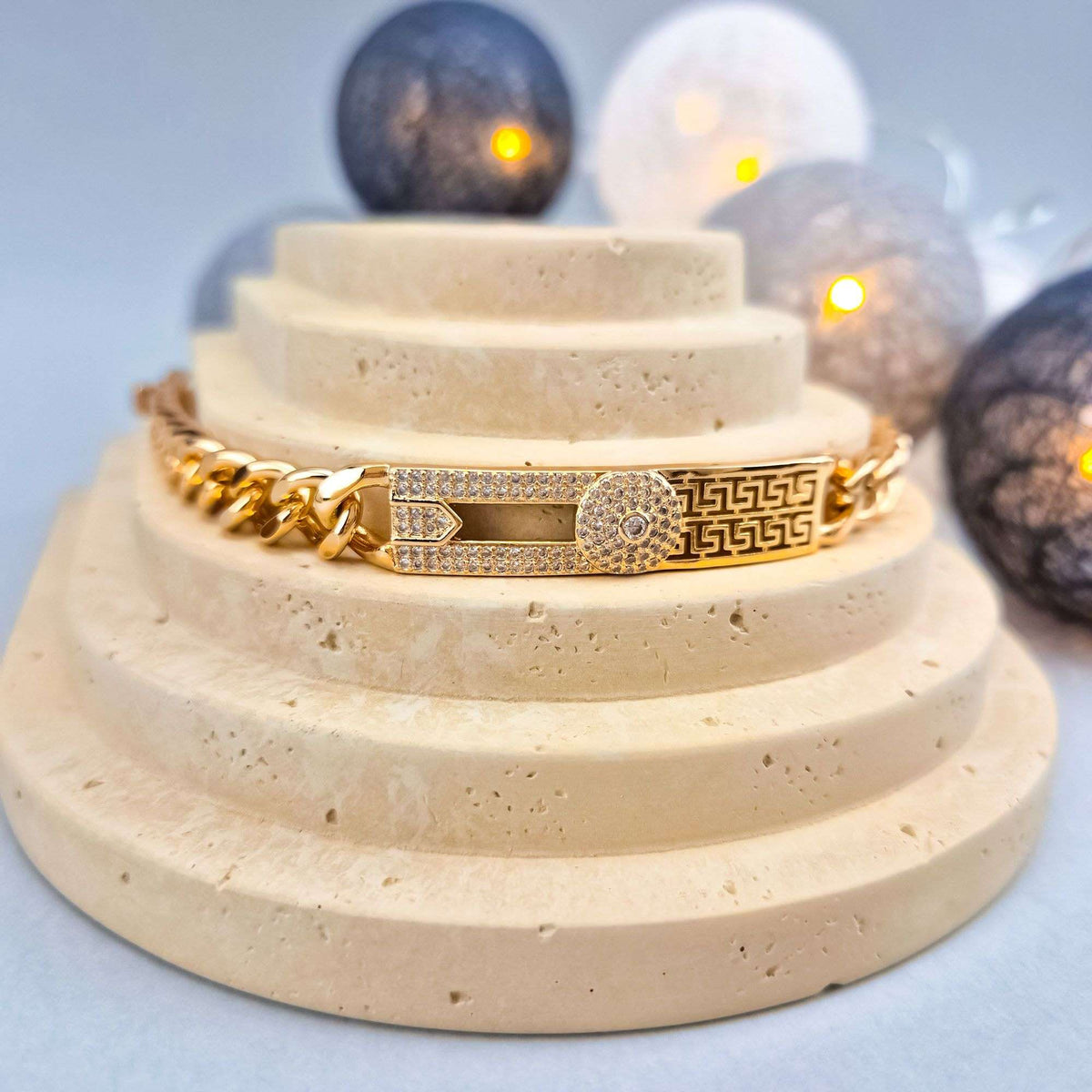 Gold-plated meander bracelet with cubic zirconia on a light stone stand