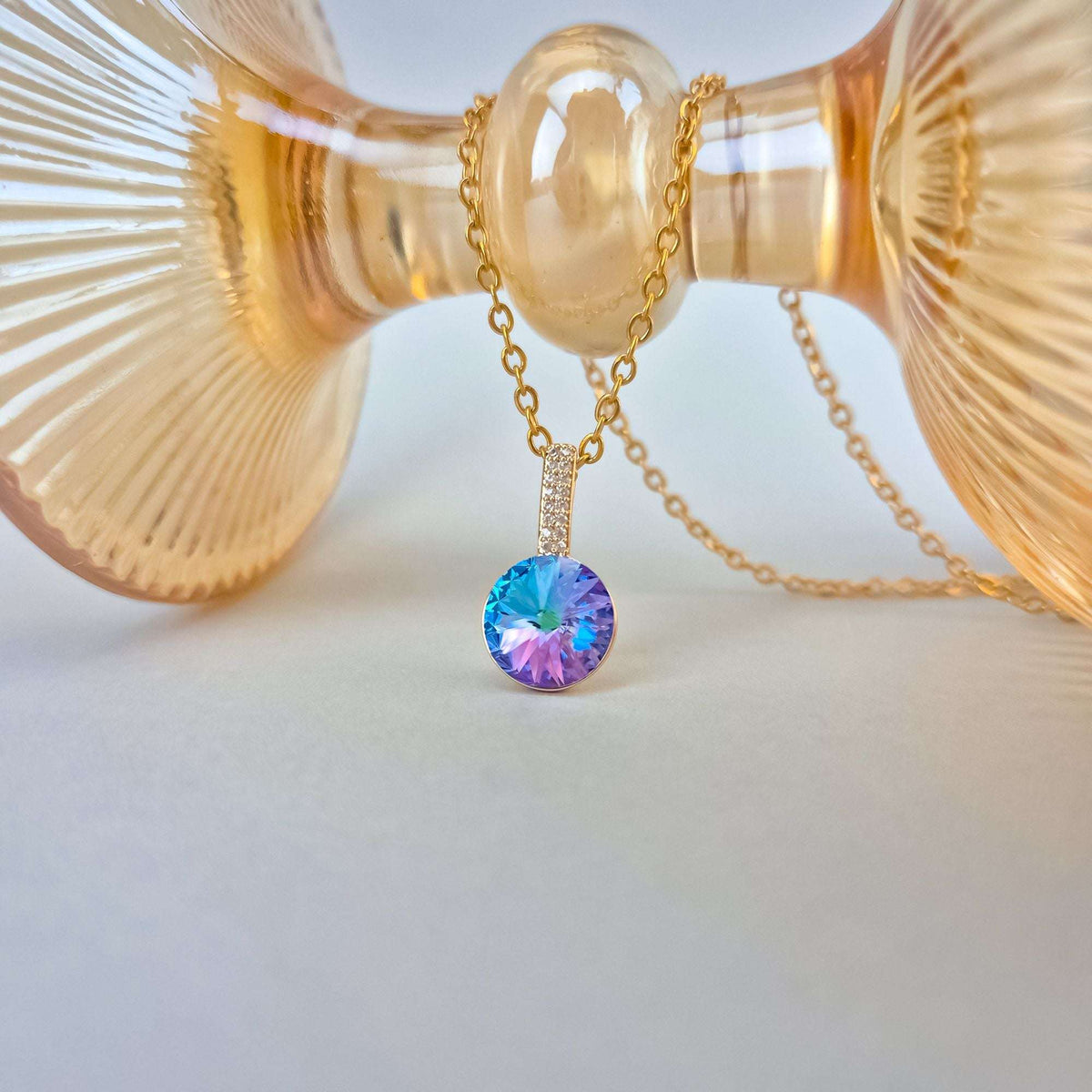 Close-up of the crystal pendant necklace draped over an amber glass dish