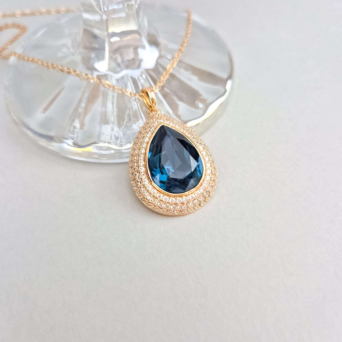 Close-up of the blue crystal pendant, its cubic zirconia rims glinting gold