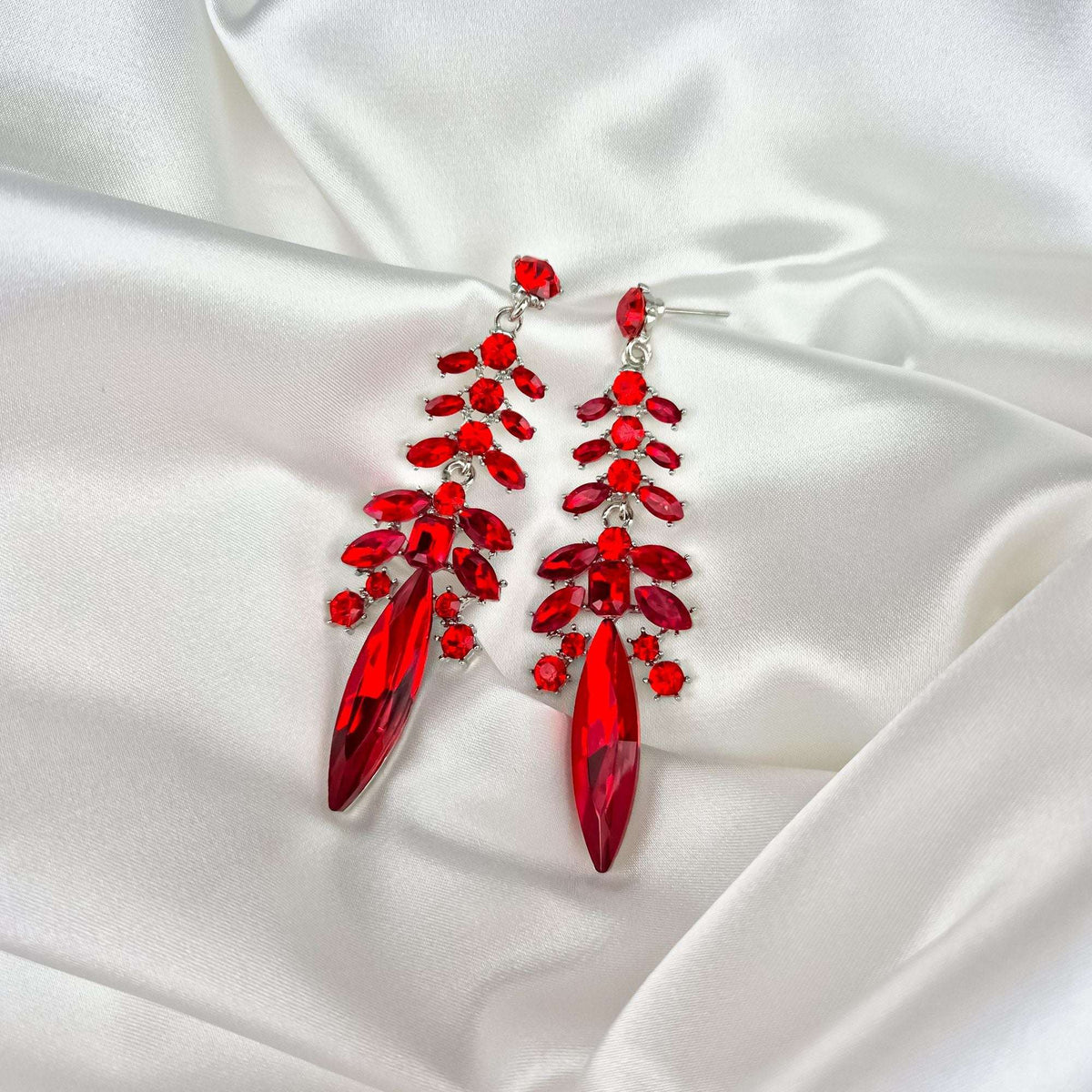 Red cubic zirconia earrings on white satin with the push-back post visible