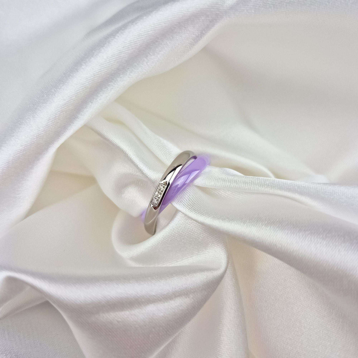 Purple ceramic ring with platinum plating, close-up on white silk folds