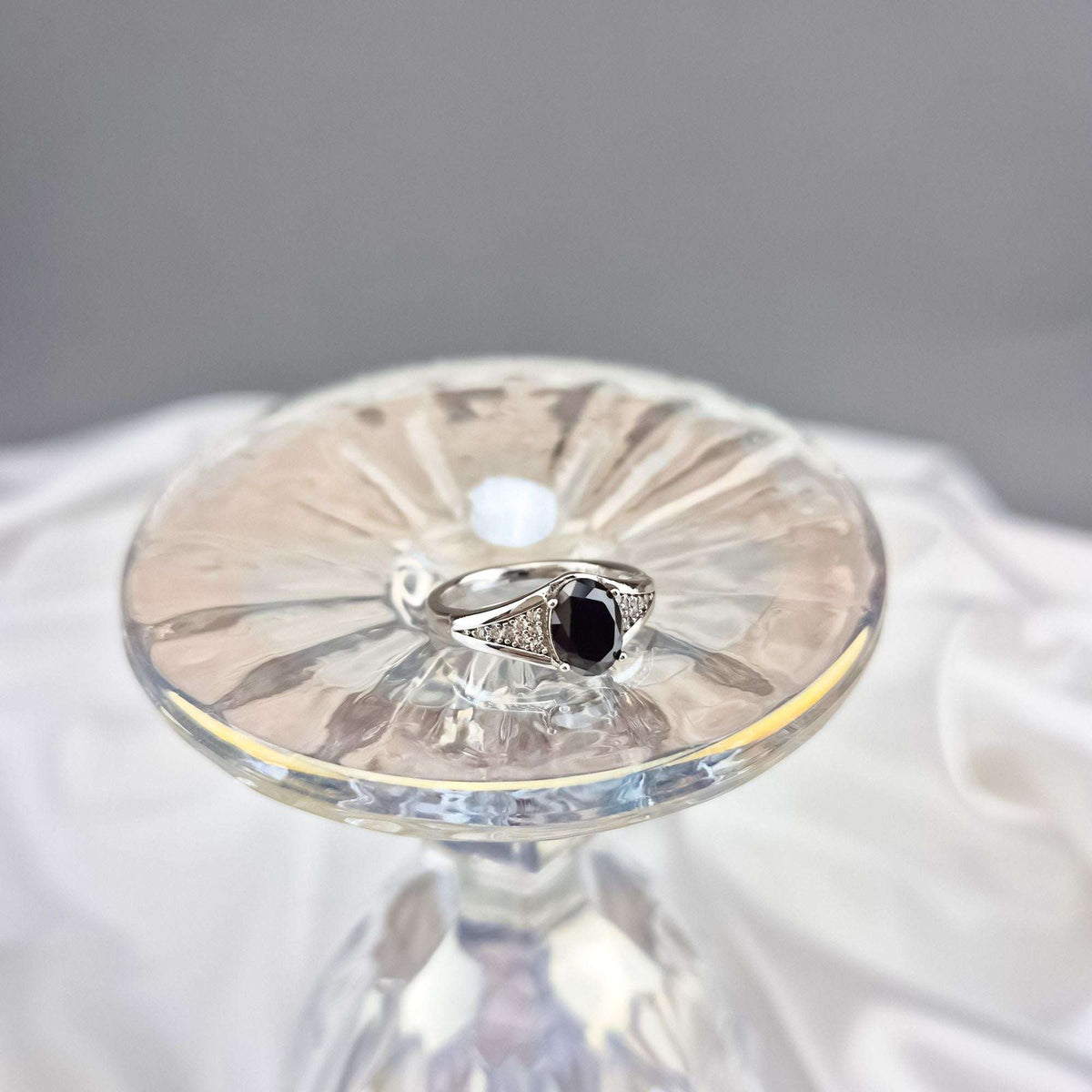 Black stone ring with cubic zirconia bands on a crystal stand, top view