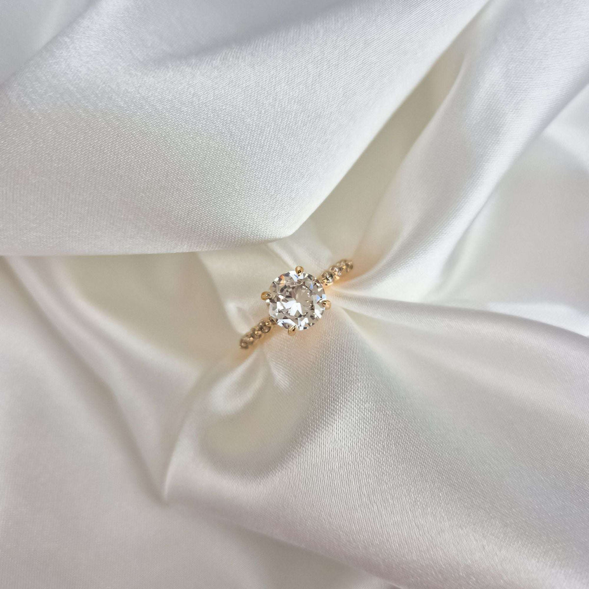 Close-up of the sparkling cubic zirconia in a gold-plated setting on cream satin