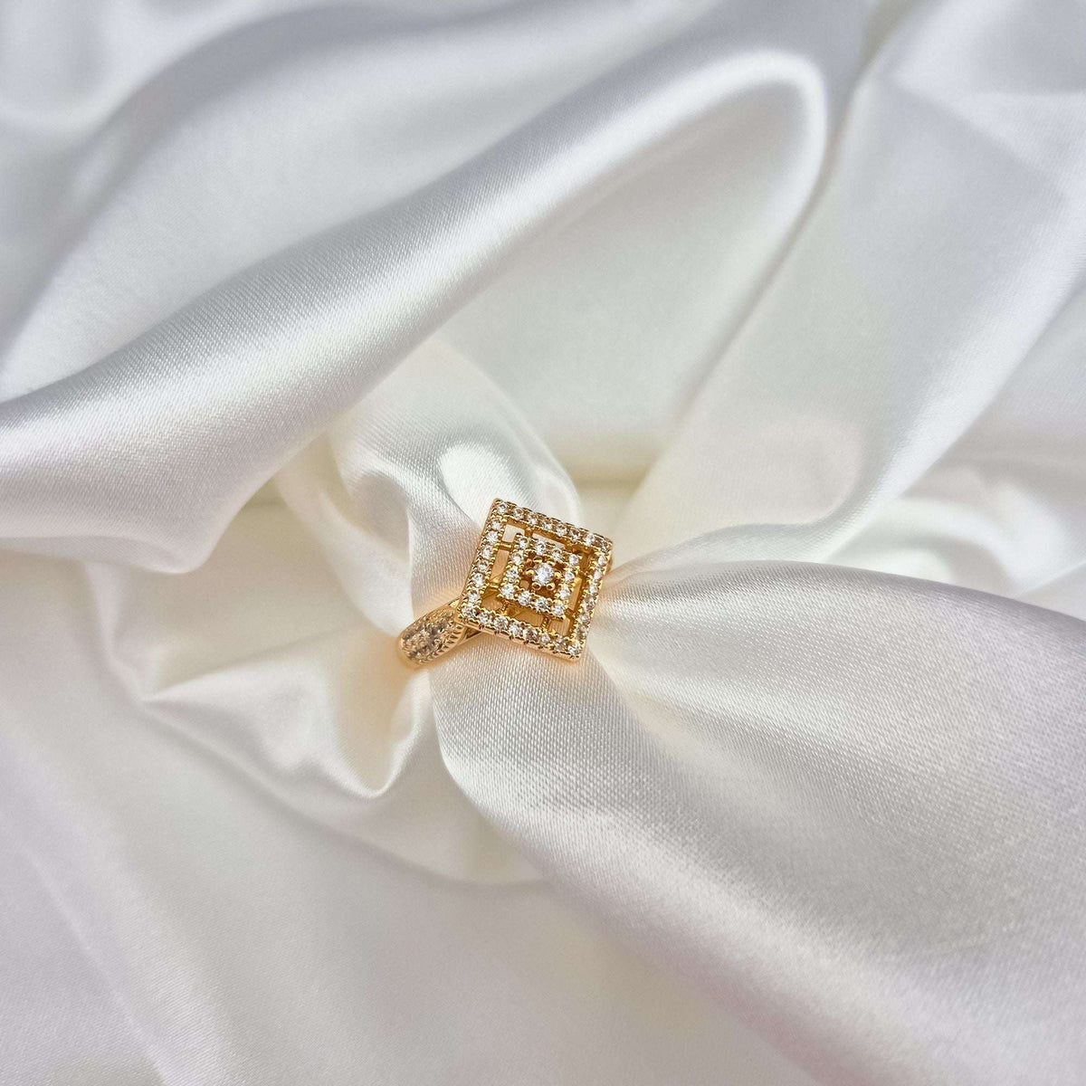 Gold-plated ring with a geometric rhombus top and white cubic zirconia on white silk