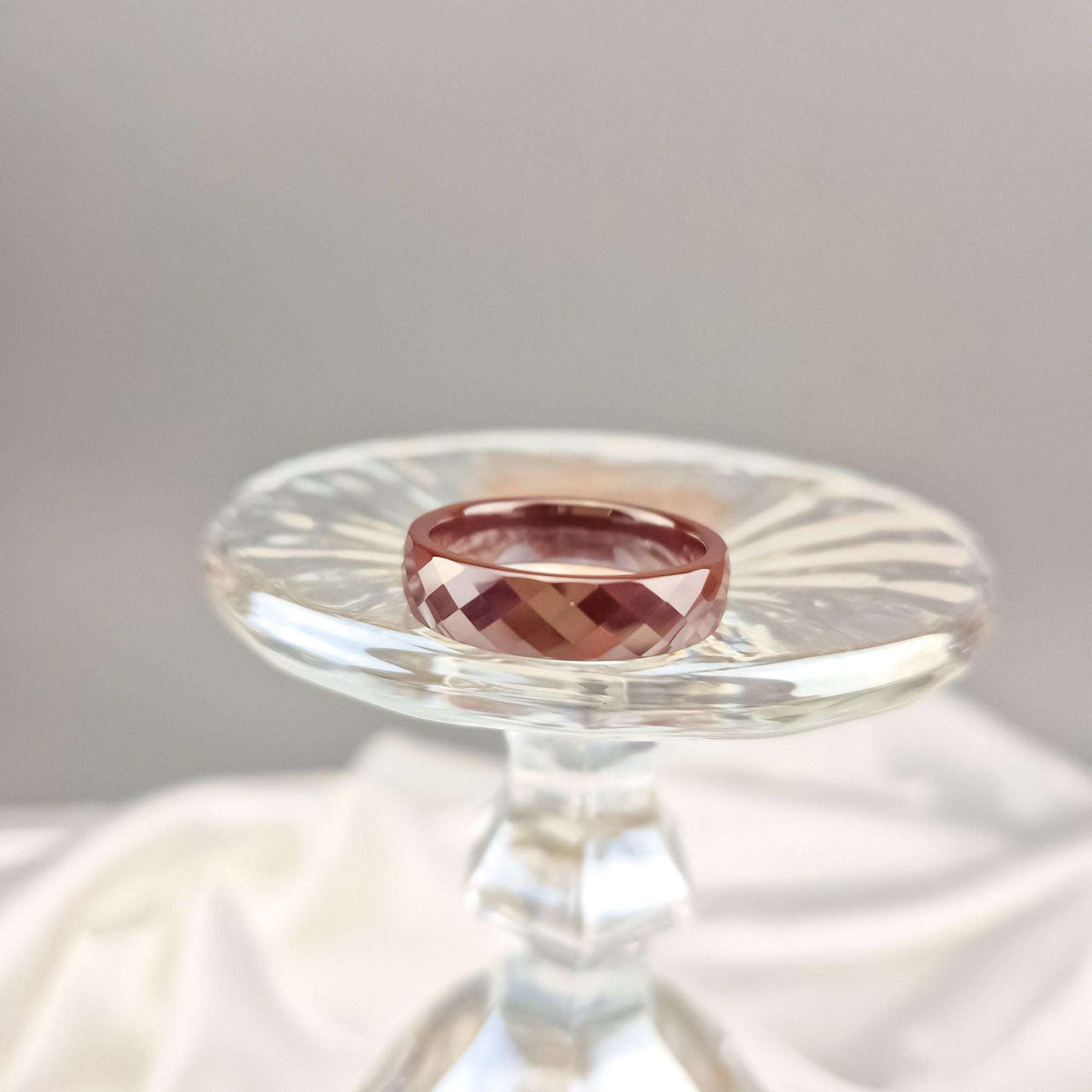 Brown ceramic ring on a crystal stand showing its cut facets