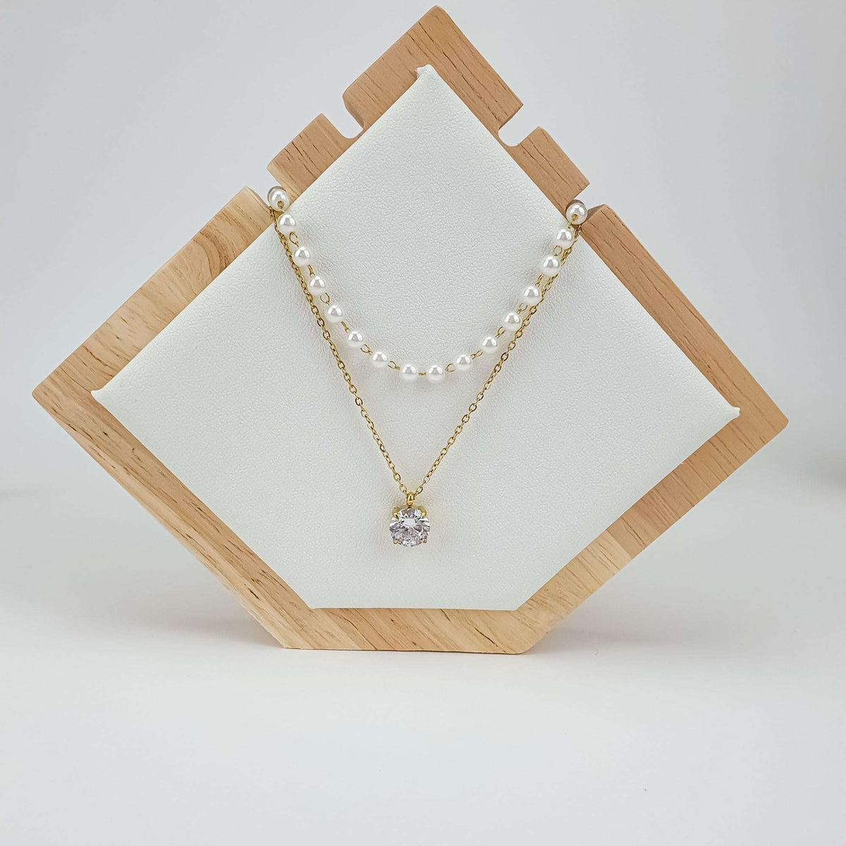 Layered necklace with pearls and a sparkling crystal on a wooden jewellery stand