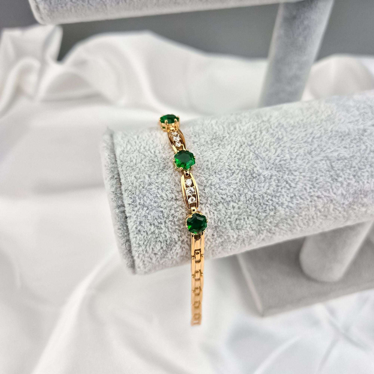 Bracelet with three emerald green crystals and cubic zirconia links on a display