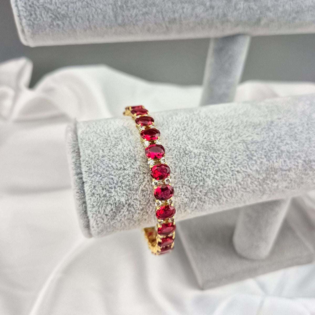 Gold-plated red crystal bracelet on a jewellery stand, close-up side view