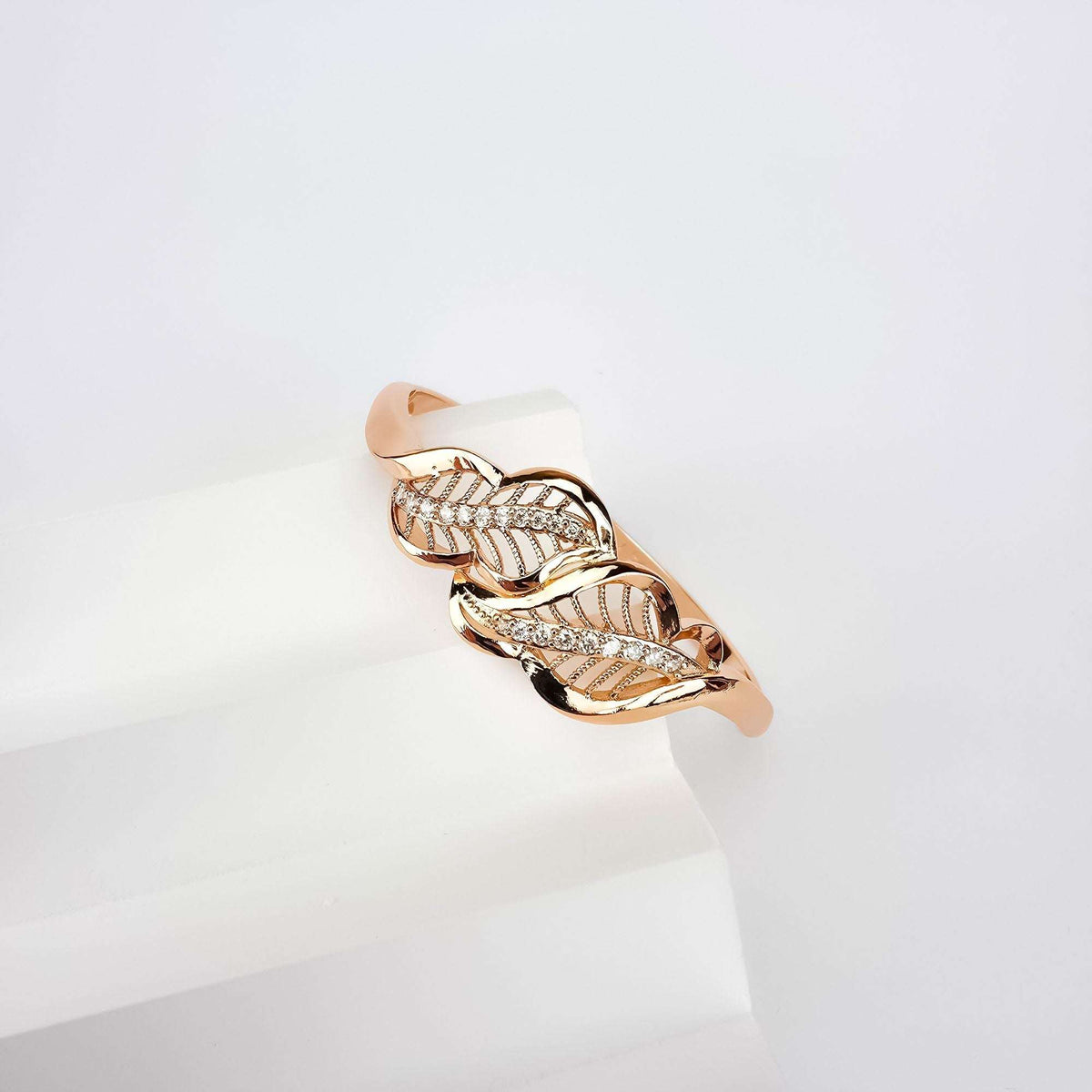 Close-up of a rose-tone bangle with an openwork leaf pattern and cubic zirconia