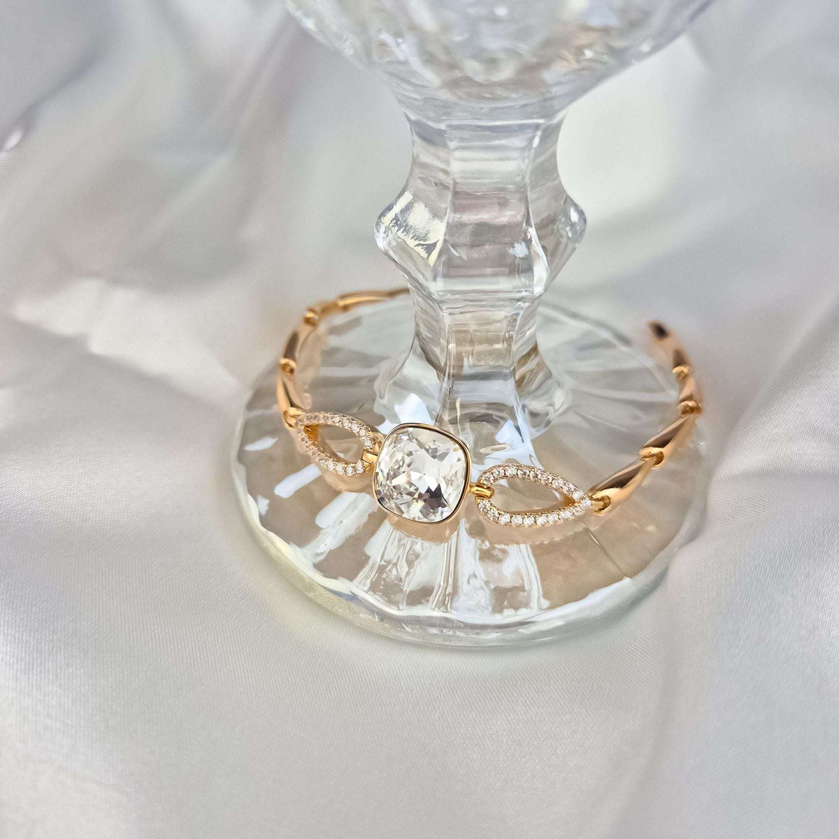 Bracelet with a sparkling crystal on a glass stand, cubic zirconia links visible