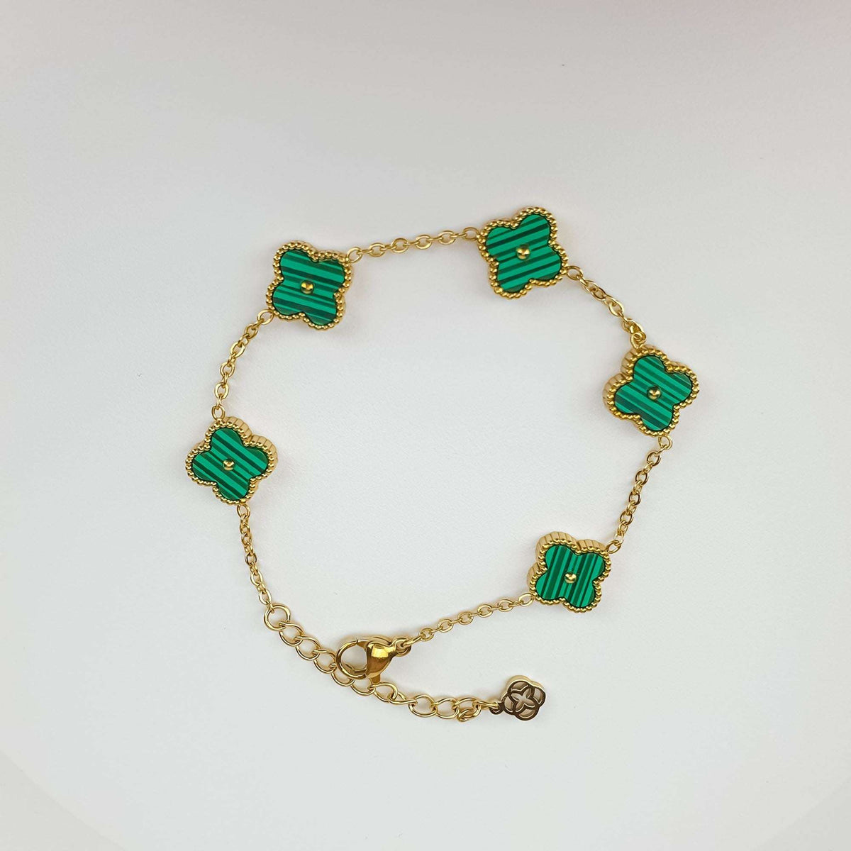 Green clover bracelet at an angle with gold plating, chain and extension charm
