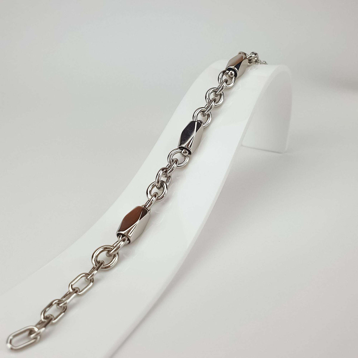 Close-up of the bracelet on a stand, shiny faceted details between round links