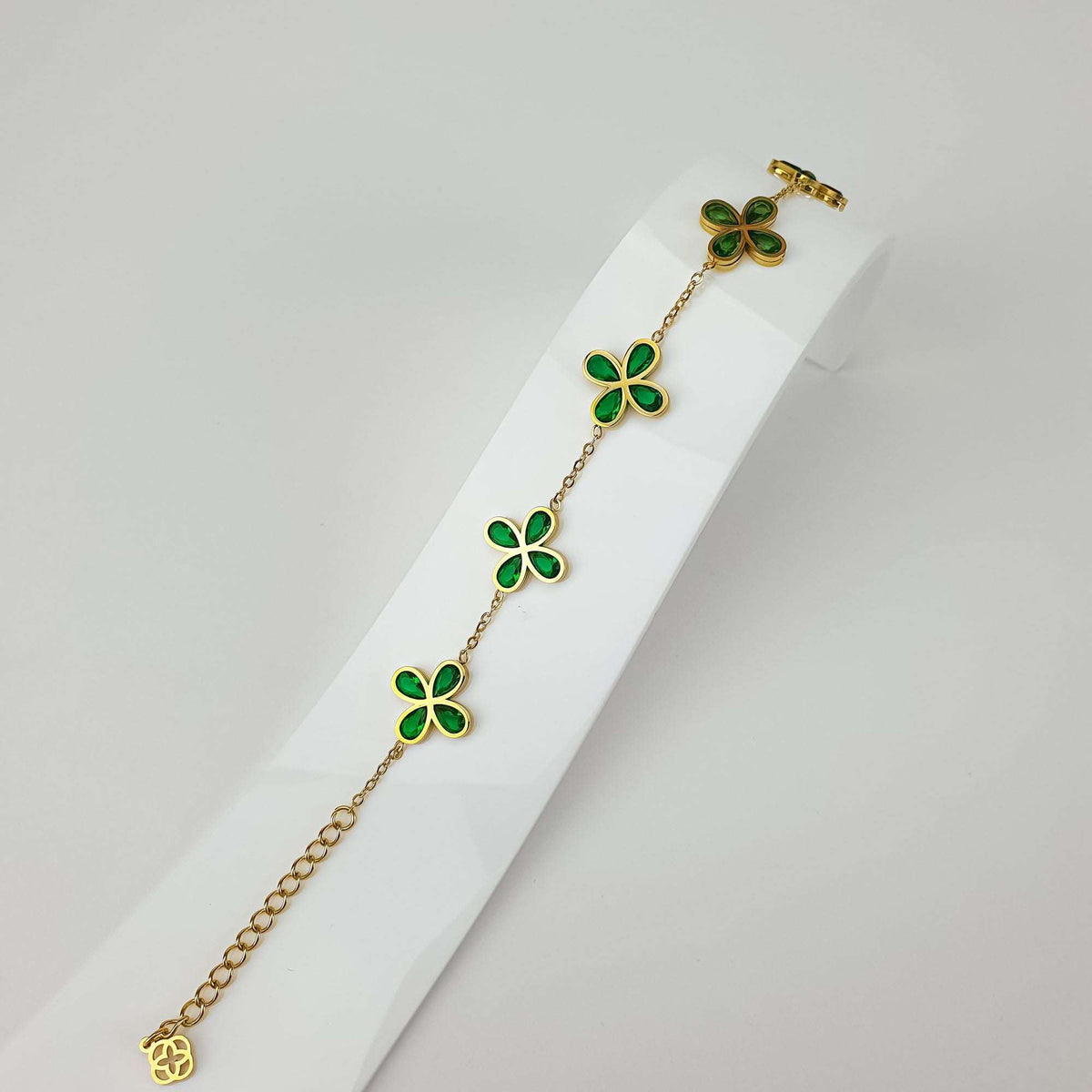 Clover bracelet with green cubic zirconia on a stand, showing the chain and extender