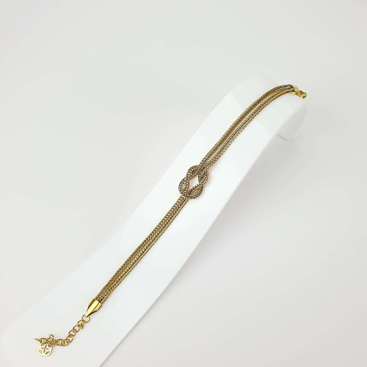 Knot bracelet on a white stand showing the weave and adjustable extension chain