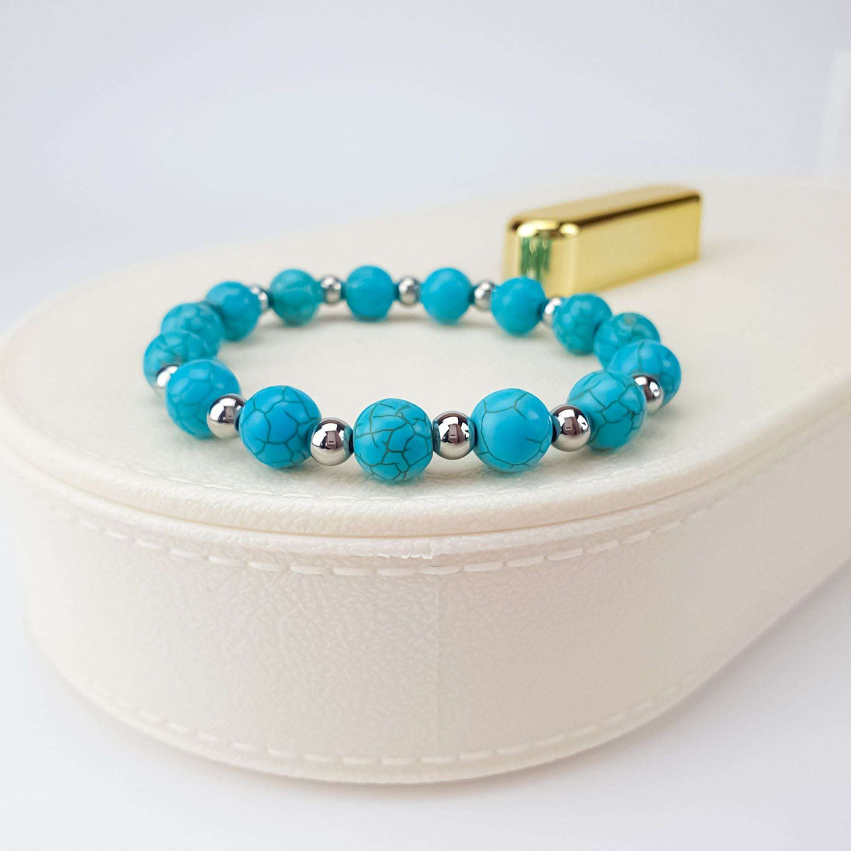 Stretch turquoise howlite bracelet with silver-tone spacers on a white box