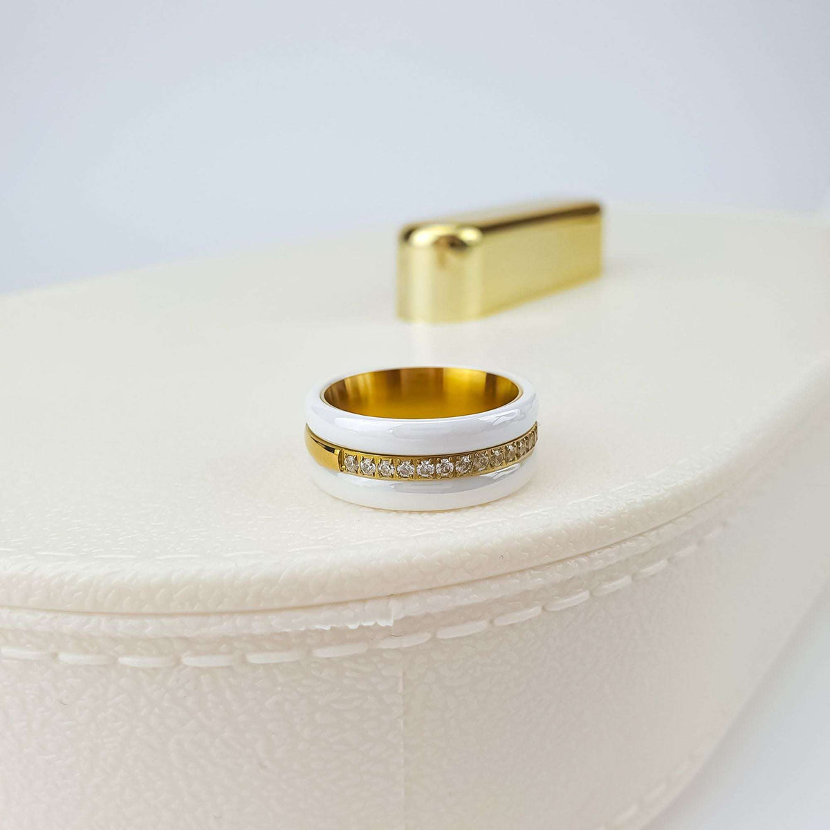 White ceramic ring with sparkling cubic zirconia standing on a pale leather box