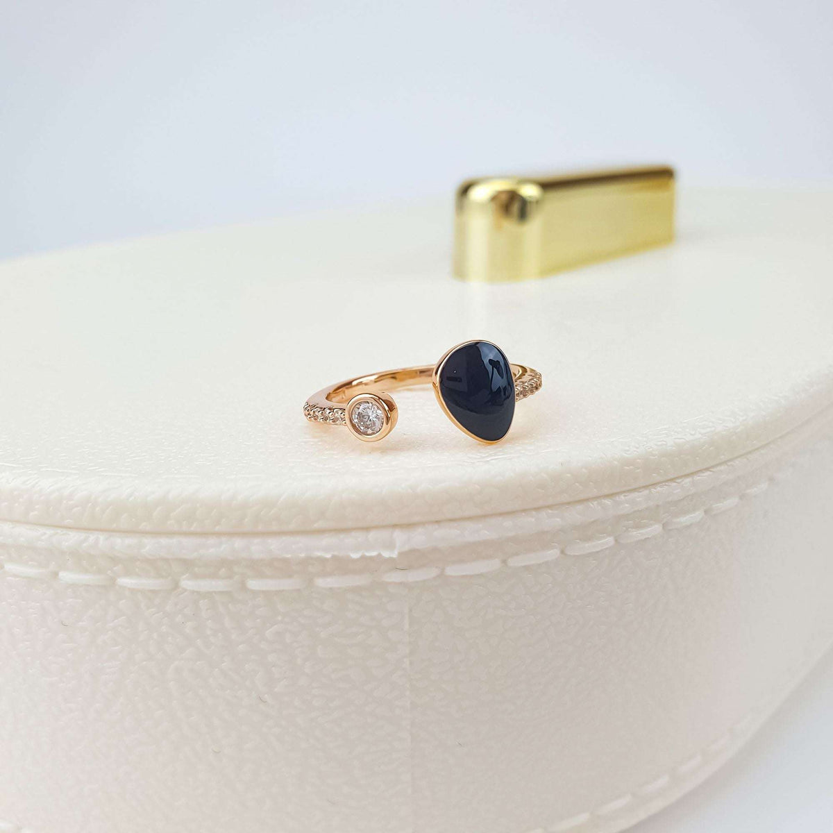 Rose gold-tone open ring with black enamel and cubic zirconia on a jewellery box