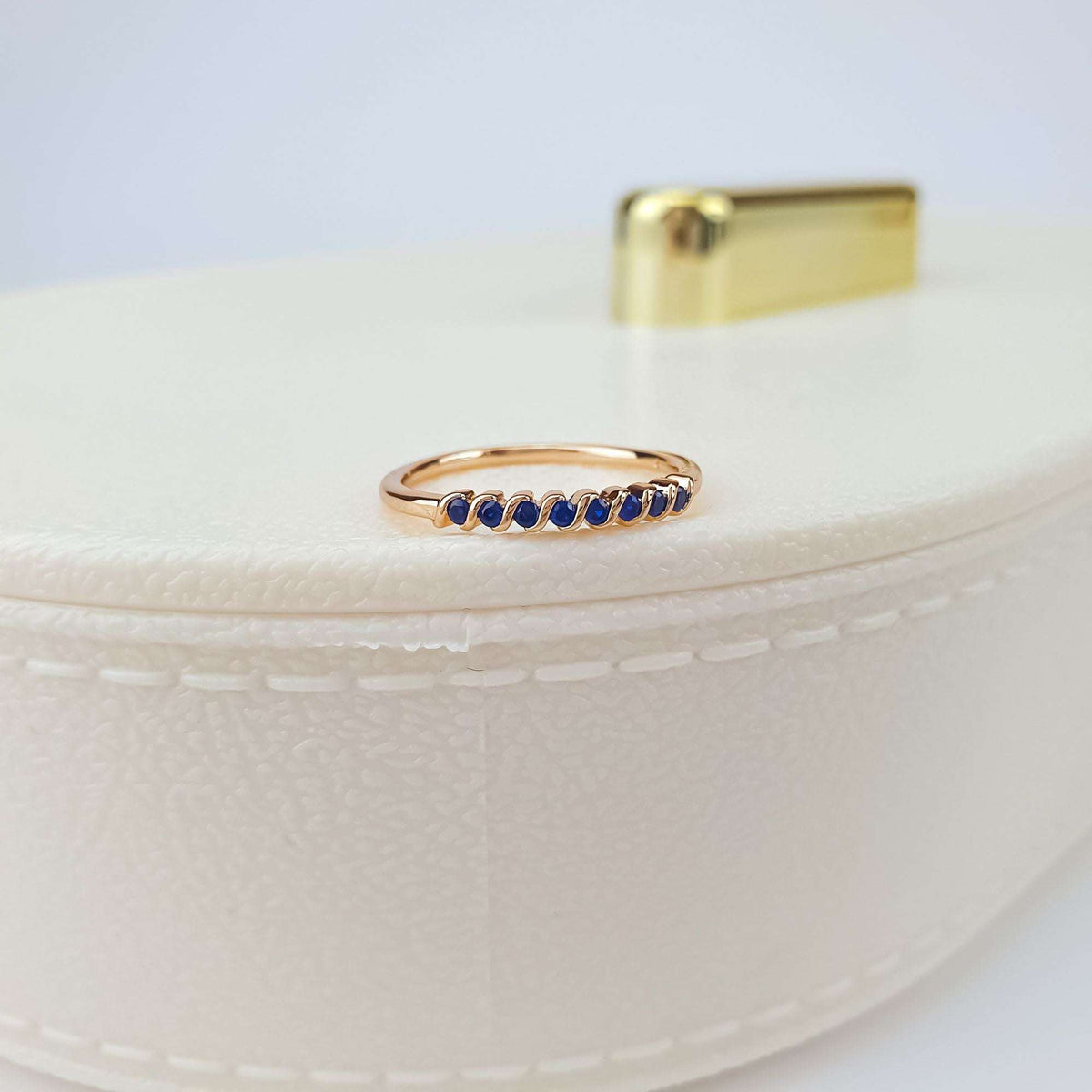 Gold-plated blue crystal ring standing on a cream box