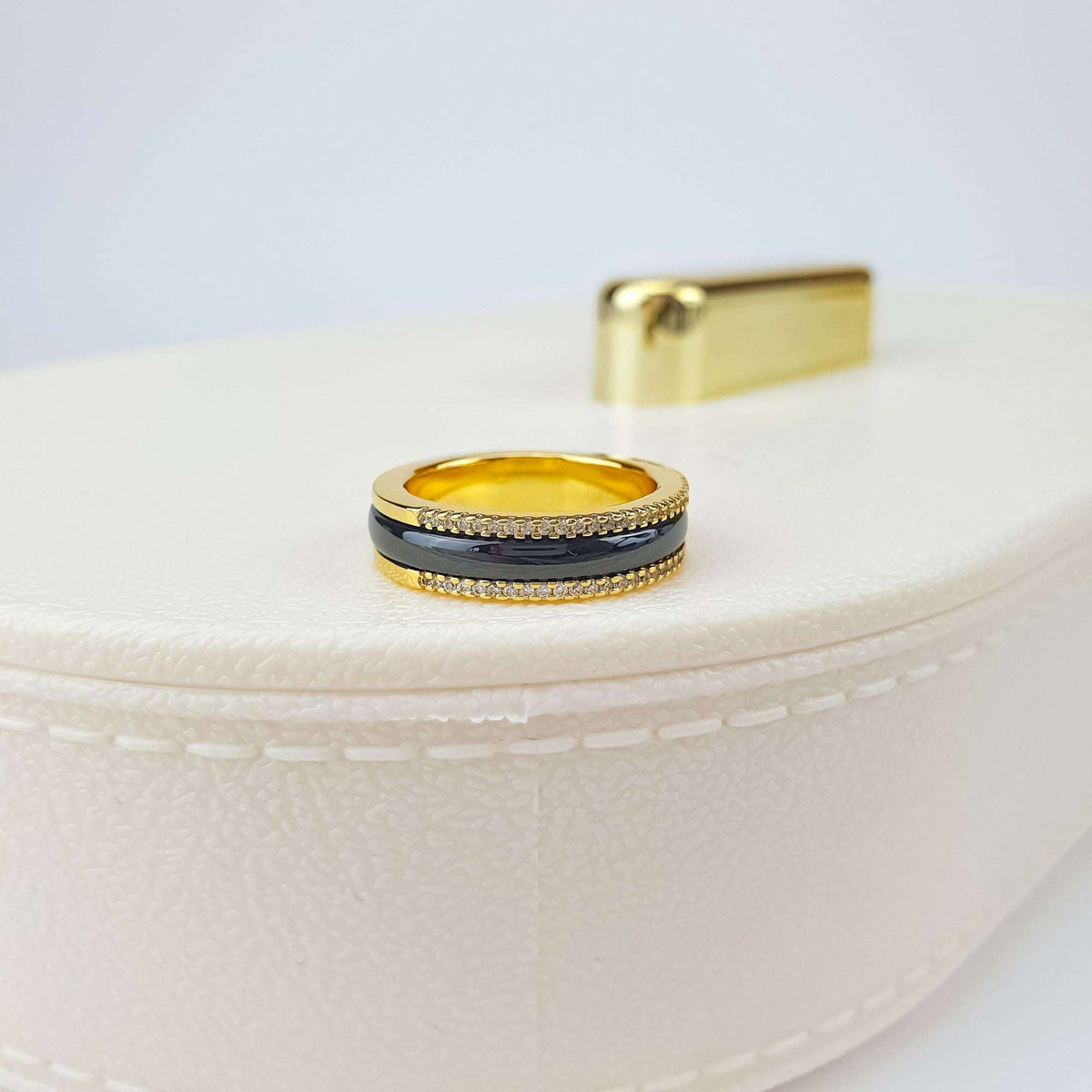 Black ceramic ring with crystal rows, side view on a light jewellery box