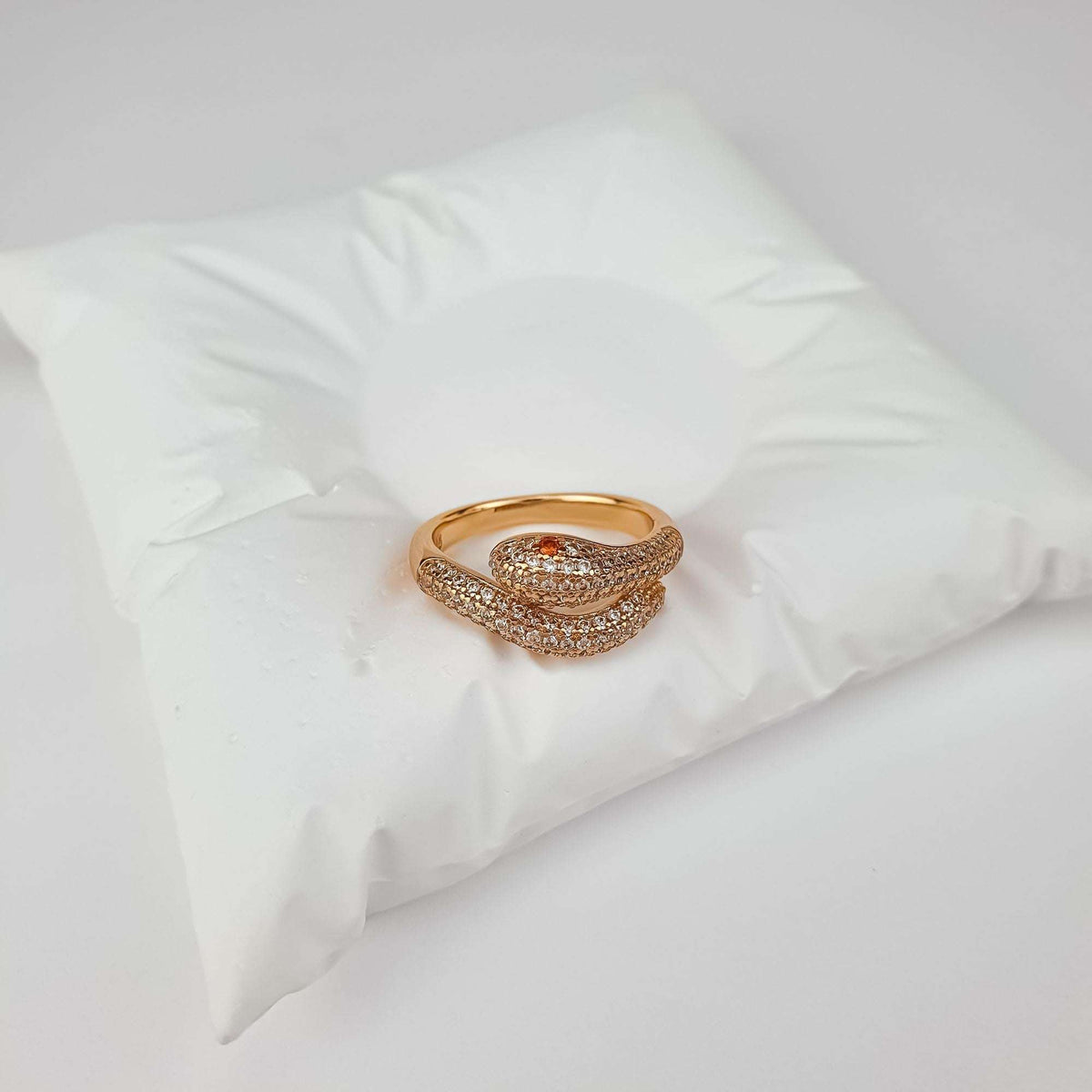 Snake ring on a white jewellery cushion, close-up of the red stone eye