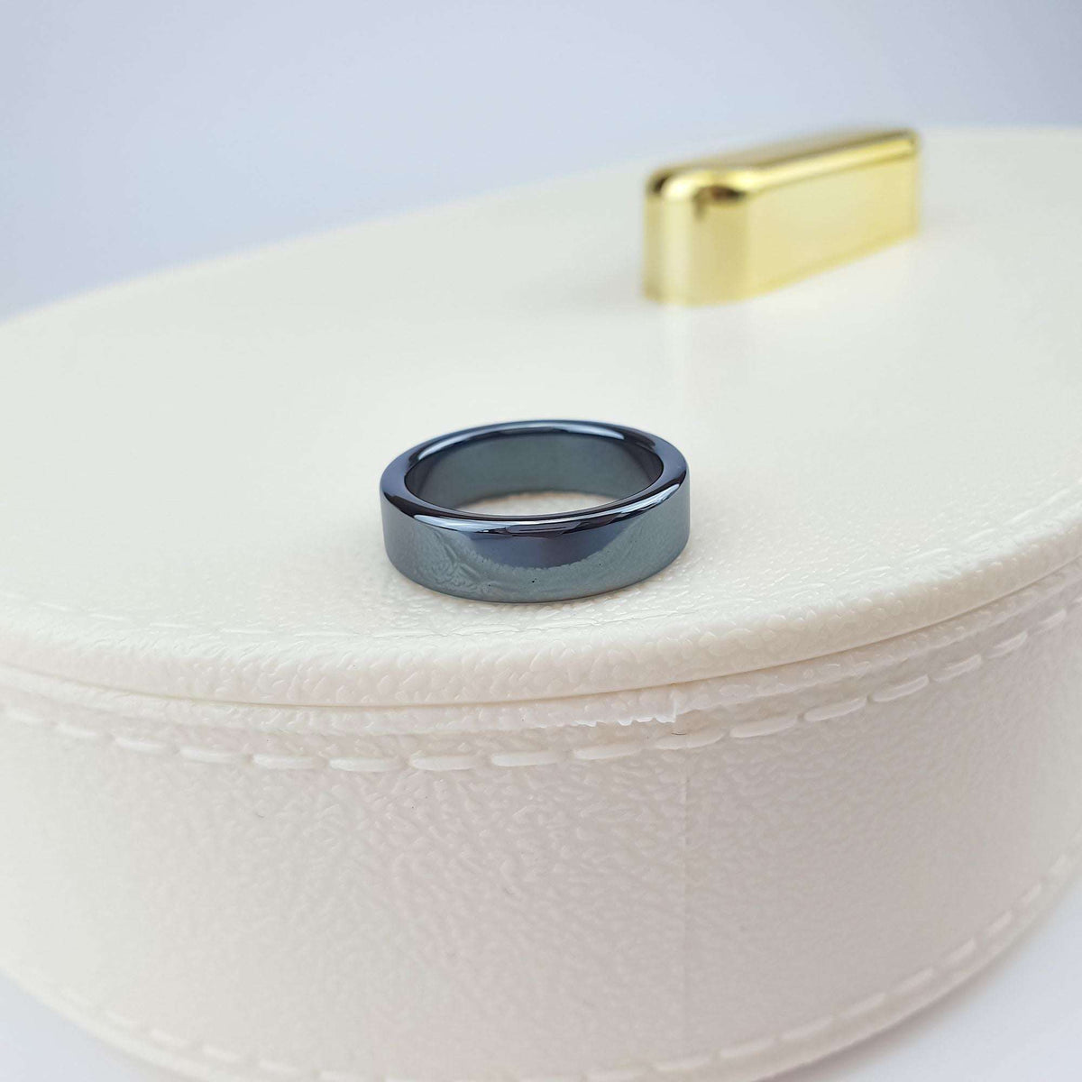 Flat hematite ring on a cream jewellery box with a gold-tone clasp