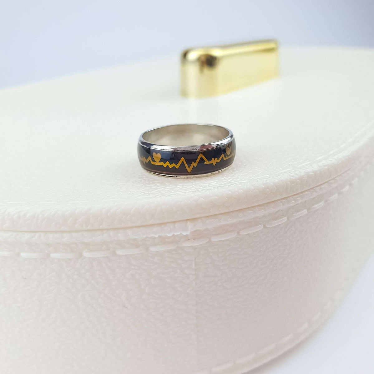 Heartbeat mood ring turned dark brown, close up on a light gift box
