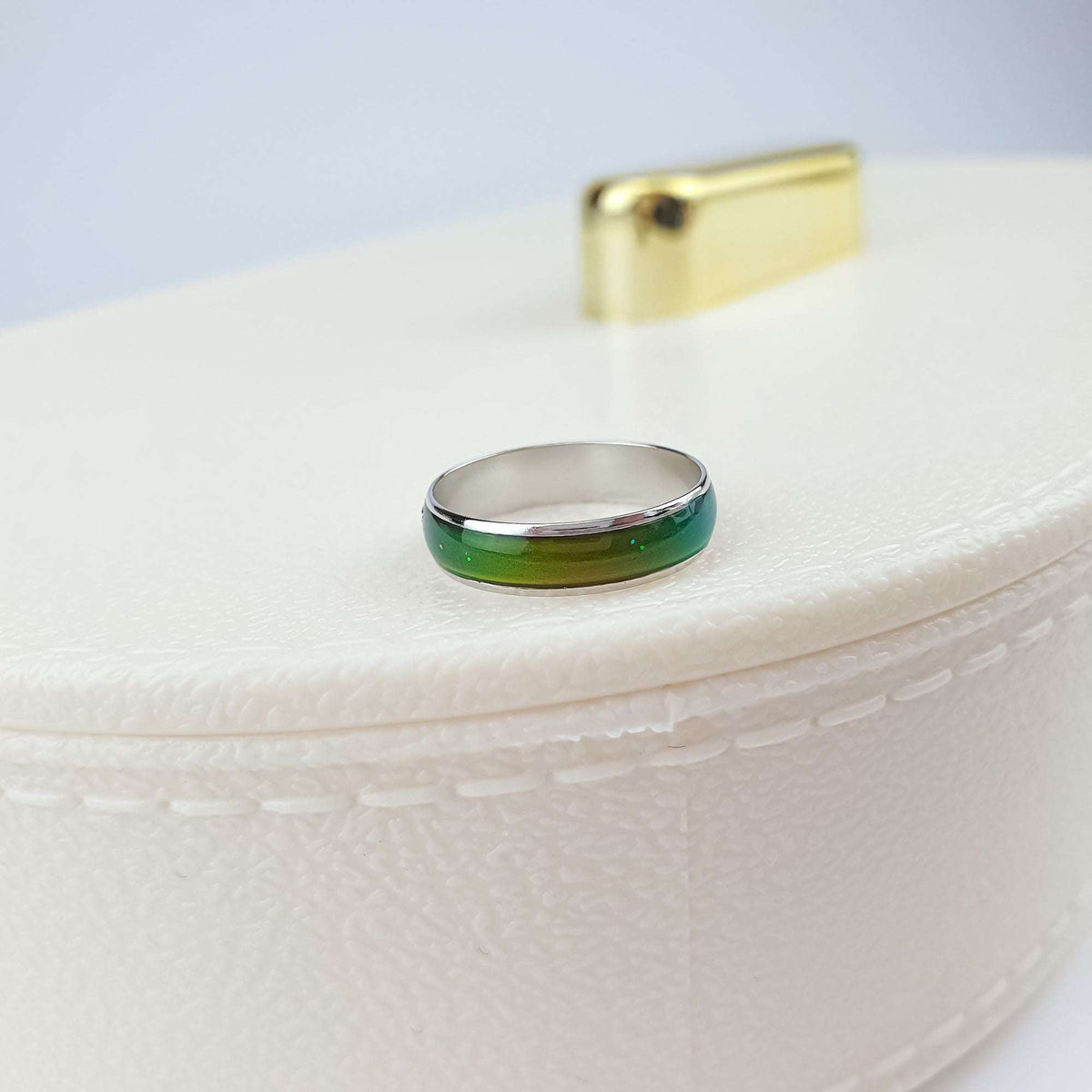 Green mood ring with shiny steel edges on a light jewellery box