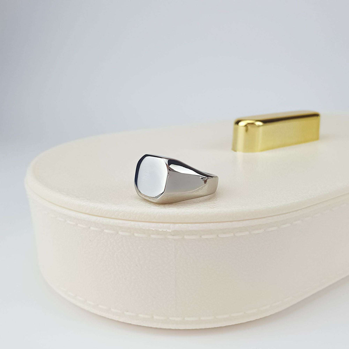 Octagonal steel ring side view on a cream jewellery box, solid band profile