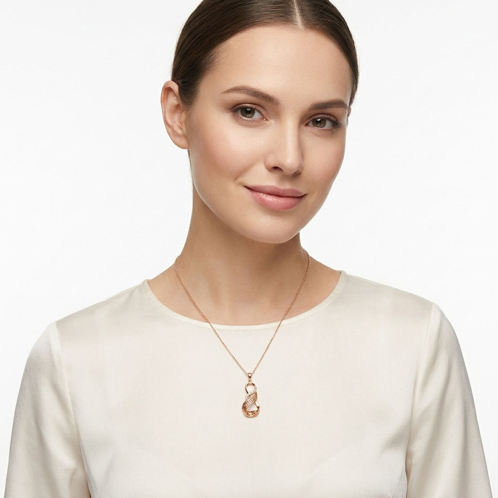 Model in a cream blouse wearing a gold-plated infinity pendant on a fine chain