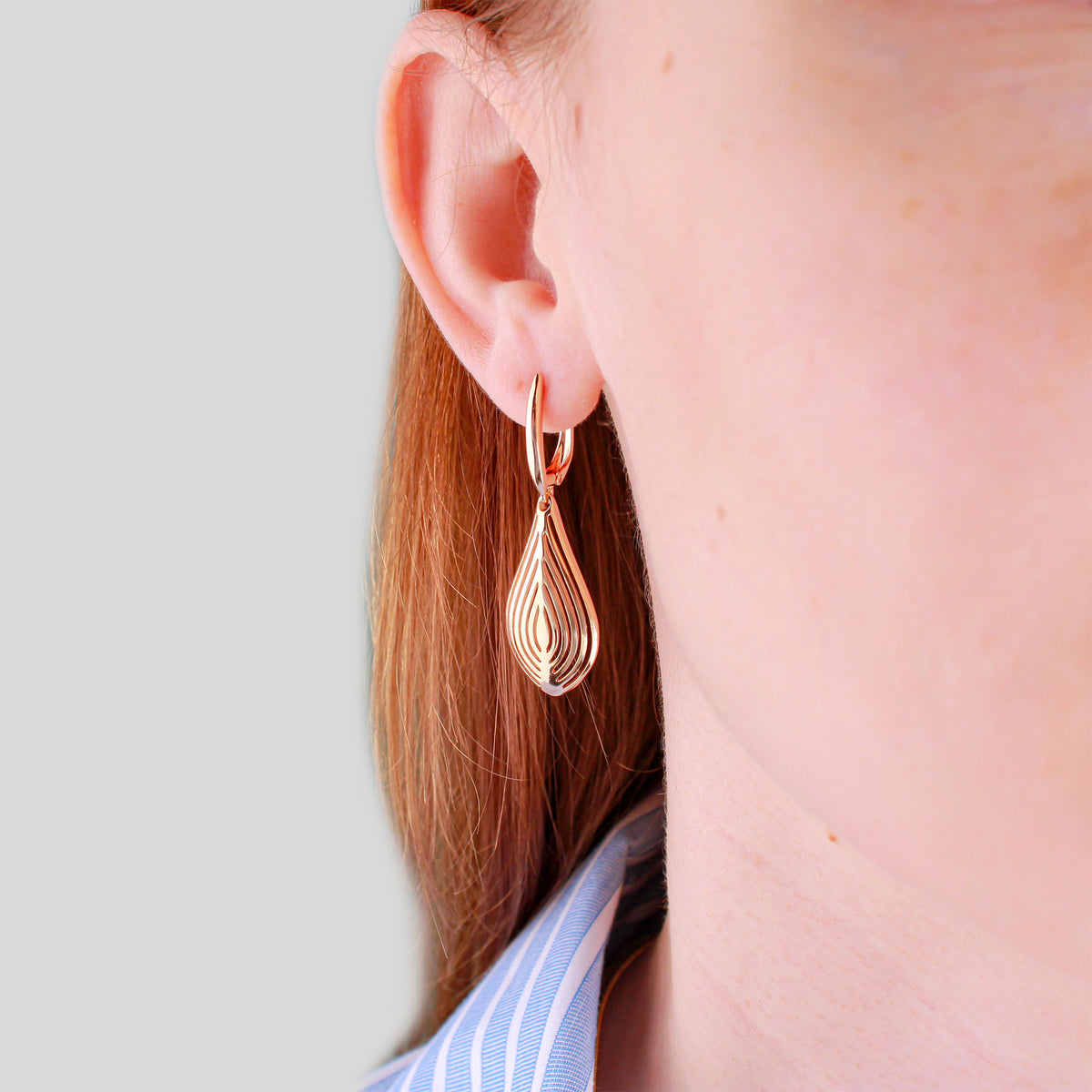 Gold-plated openwork teardrop earring worn on a model's ear
